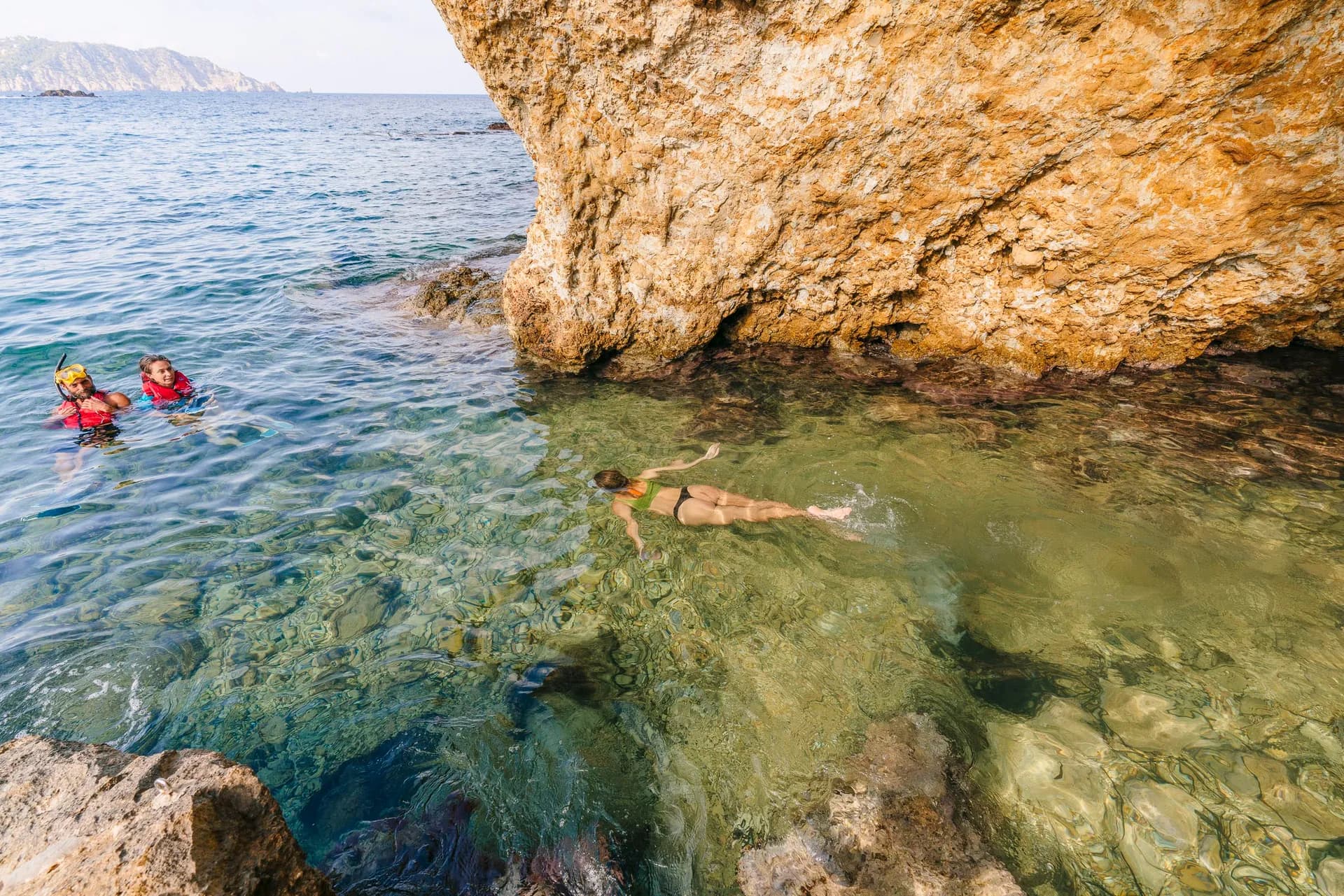 Snorkelling in crystal-clear water by a sea cave